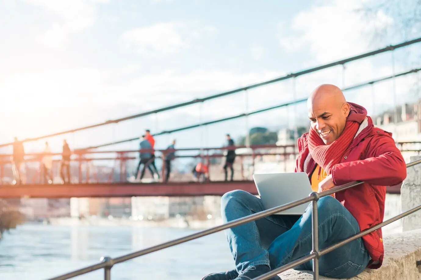 Glatzköpfiger lateinamerikanischer Mann, der im Freien an einem Laptop arbeitet.